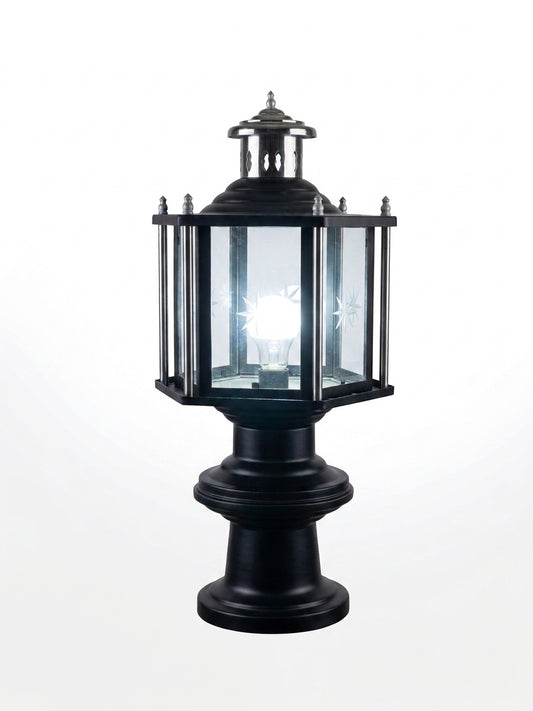 A black metal post cap lantern with clear glass panels and a glowing White light bulb inside, shown against a plain white background.