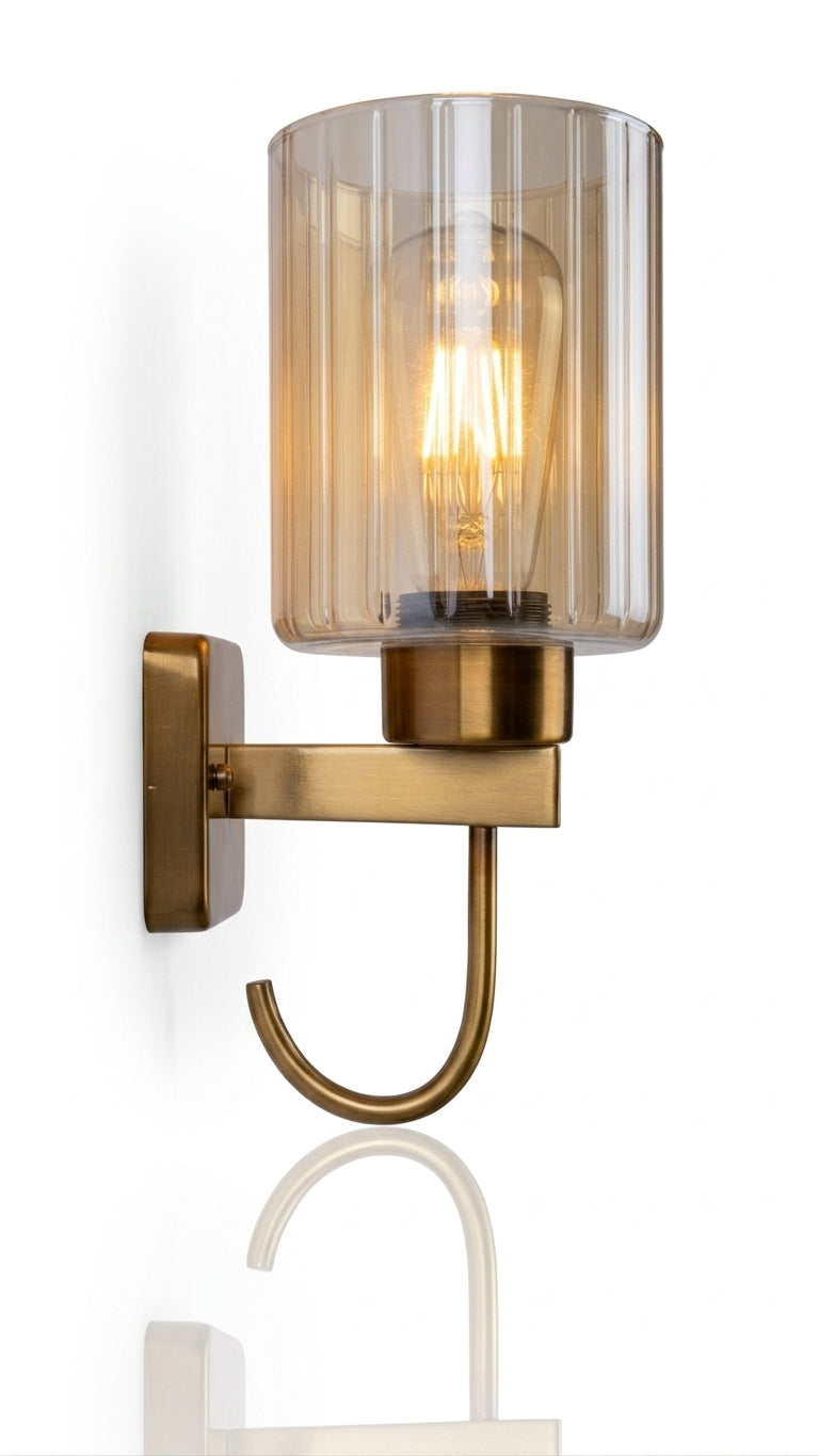 A macro photograph focused purely on the center of the sconce, capturing the intricate detail of the glowing Edison-style LED filament, its warm golden light, and the clear fluting of the surrounding glass shade, which creates repeating vertical highlights.
