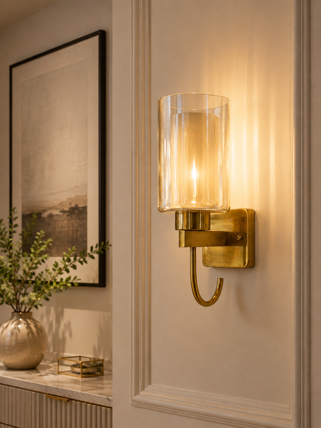 Modern brass glass wall sconce illuminating an elegant interior hallway