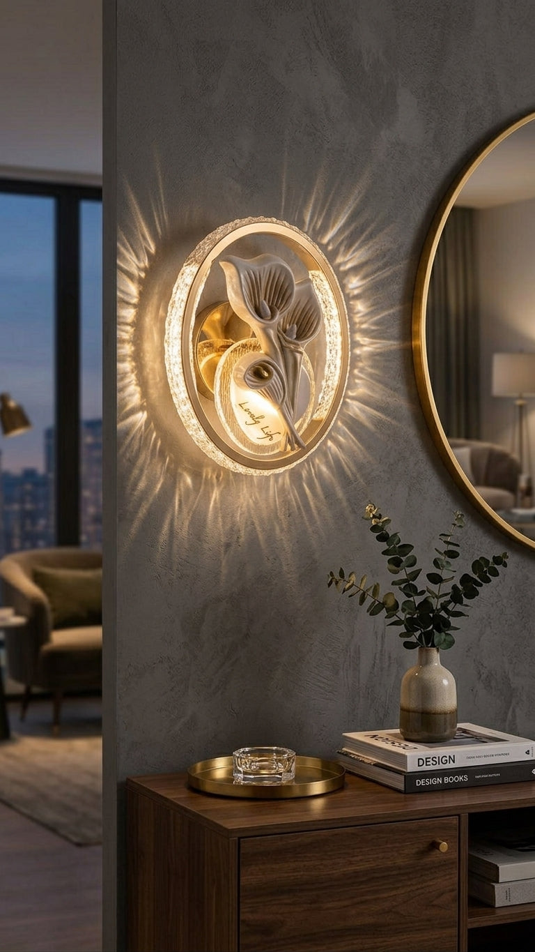 A modern wall-mounted light fixture with a glowing sunburst effect, featuring a circular frame and sculptural floral elements, installed on a textured gray wall in a stylish interior setting.