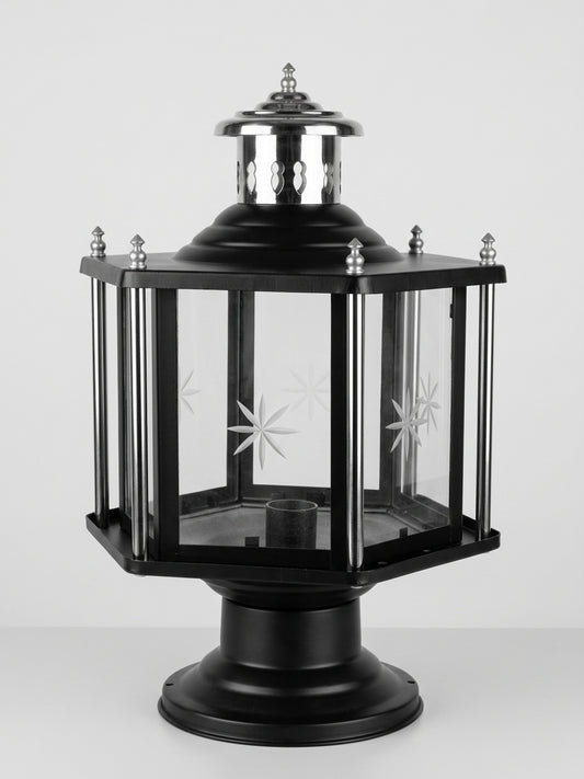 A black metal lantern-style outdoor light with clear glass panels, decorative starburst cutouts, and silver-toned finials, shown on a light gray studio background.