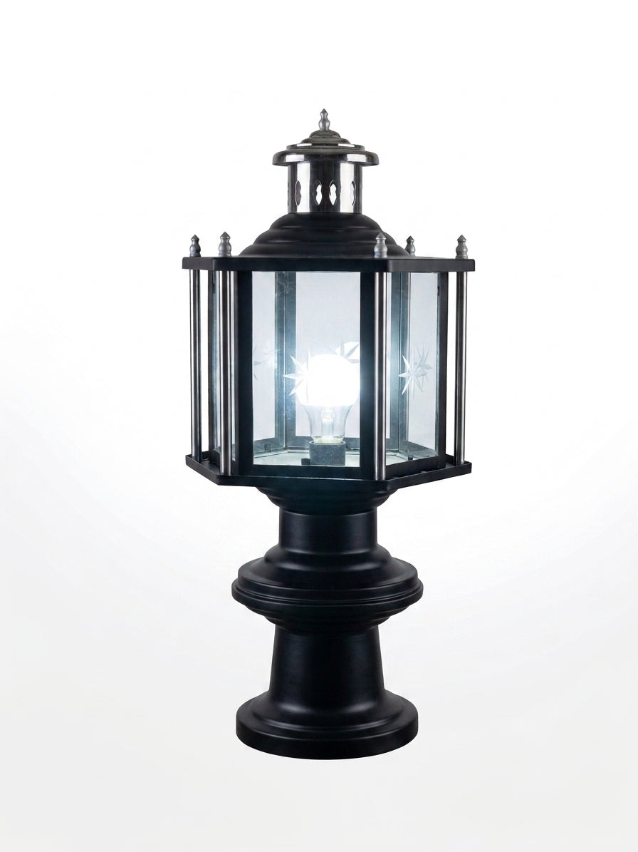 A black metal post cap lantern with clear glass panels and a glowing White light bulb inside, shown against a plain white background.