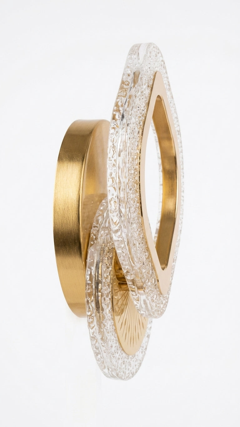 A luxury wall sconce featuring interlocking organic-shaped gold and clear textured acrylic rings, photographed against a seamless white background.