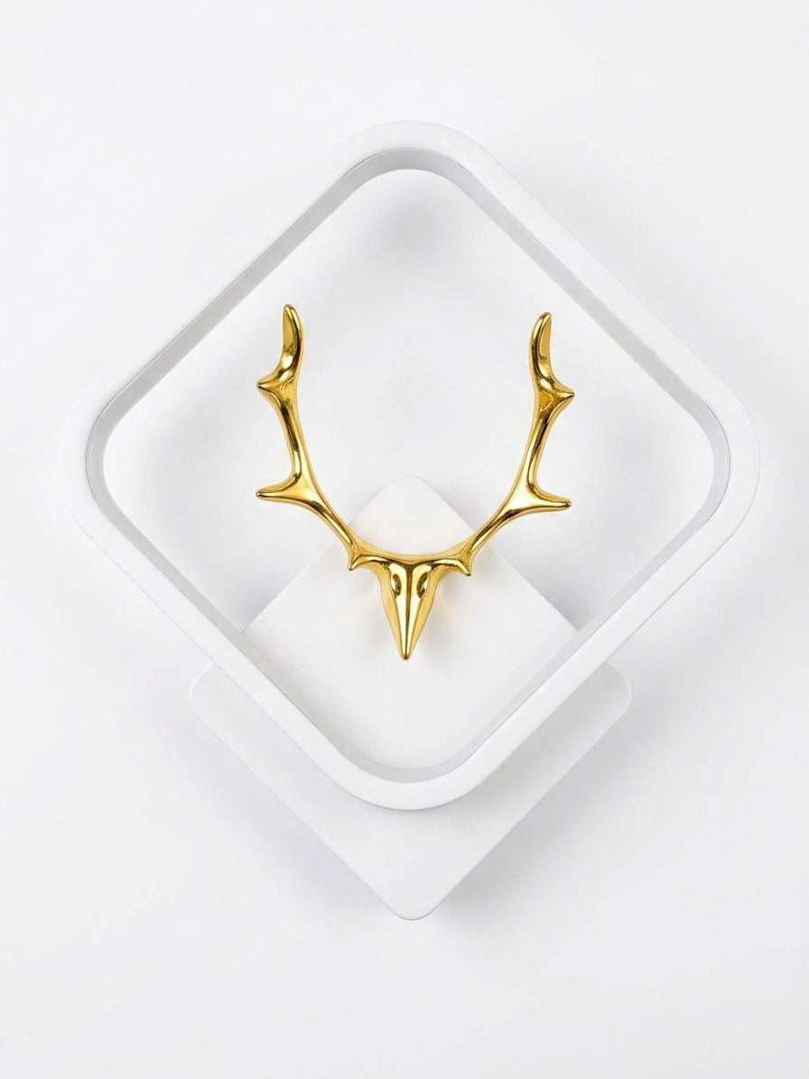 A polished gold deer head antler wall mount displayed on a white geometric stand against a clean white background.