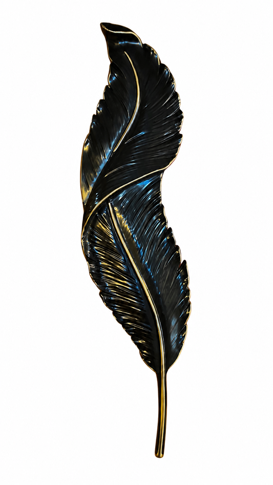 A decorative feather-shaped wall piece or ornament in glossy black enamel with gold-toned edging and a gold stem, shown against a plain white background.
